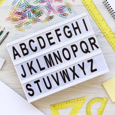 Back to school concept. Letters from A to Z. English alphabet on a lightbox, accessories for study on a white wooden background, top view. From above, flat lay, overhead.の写真素材