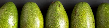 Whole avocados on a black background, top view. Overhead, from above, flat lay. Close-up.
