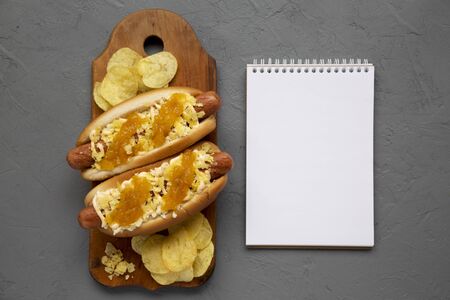 Homemade colombian hot dogs with pineapple sauce, chips and mayo ketchup on a rustic wooden board,...