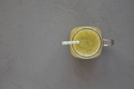 Homemade green cucumber apple smoothie in a glass jar on a gray surface, top view. Flat lay, overhead, from above. Copy space.の写真素材
