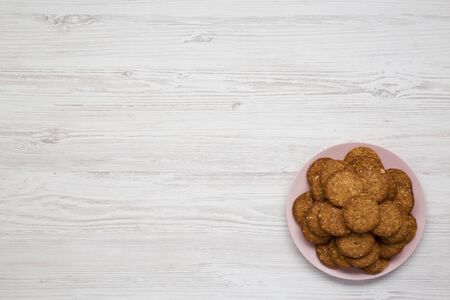 Cereal cookies on a pink plate on a white wooden surface, top view. Flat lay, overhead, from above. Copy space.の写真素材