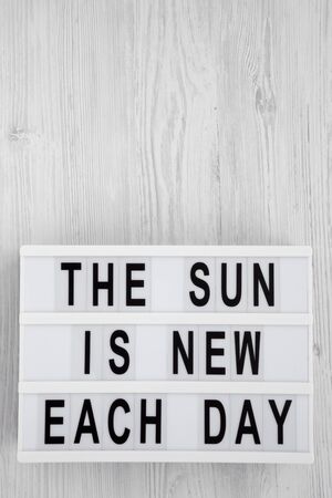'The sun is new each day' words on a lightbox on a white wooden background, top view. Overhead, from above, flat lay. Copy space.の写真素材