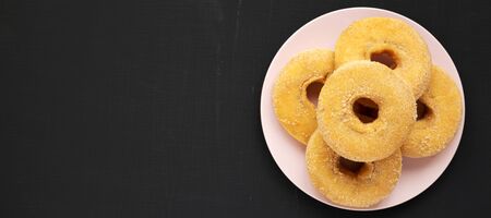 Homemade autumn apple-cinnamon donuts on a pink plate on a black surface. Flat lay, overhead, top view. Space for text.の写真素材