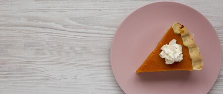 Homemade Thanksgiving pumpkin pie on a pink plate on a white wooden background, top view. Overhead, from above, flat lay. Space for text.の写真素材