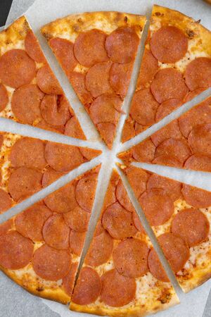 Hot Pepperoni pizza on parchment over black background, top view. Close-up.の写真素材