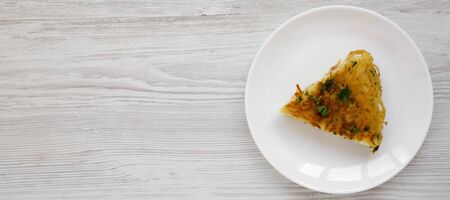 Homemade spaghetti omelette on a white plate on a white wooden surface, top view. Flat lay, overhead, from above. Space for text.の写真素材