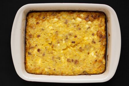 Homemade Cheesy Amish Breakfast Casserole on a black background, overhead view. Flat lay, from...