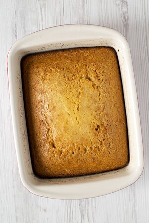 Homemade sweet Cornbread in a dish over white wooden background, top view. Flat lay, overhead, from...