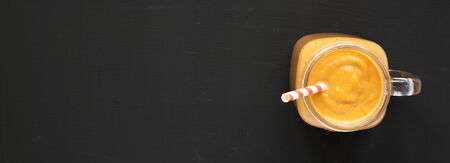 Homemade pumpkin smoothie in a glass jar over black surface, top view. Flat lay, overhead, from above. Copy space.の写真素材