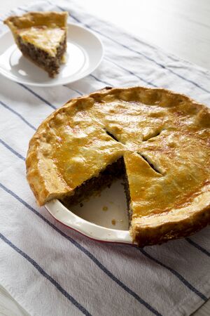 Tasty Homemade Canadian Tourtiere Meat Pie on a white plate , side view. Close-up.