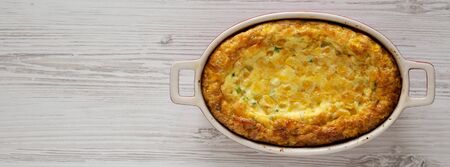 Homemade Cheddar Corn Pudding Casserole on a white wooden surface, top view. Flat lay, top view,...