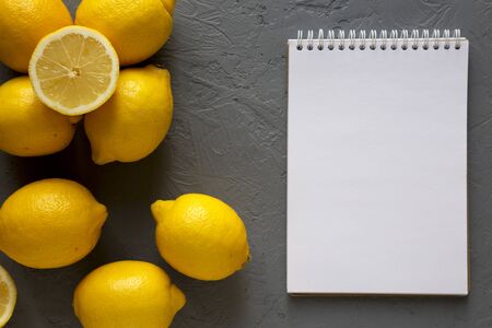 Fresh Ripe Yellow Organic Lemons, blank notepad on gray background, top view. Flat lay, overhead, from above. Copy space.の写真素材
