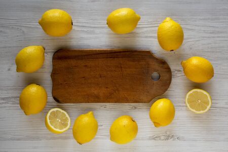 Ripe Yellow Organic Lemons and rustic board on a white wooden background, overhead view. Flat lay, top view, from above. の写真素材