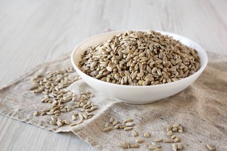 Raw Sunflower Seed Kernels in a white bowl on a white wooden background, side view. Close-up.の写真素材