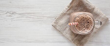 Homemade New England Chocolate Milkshake in a Glass Jar Mug on a white wooden table, top view. Overhead, from above, flat lay. Space for text.の写真素材