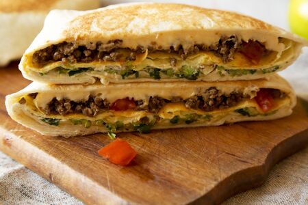 Tasty Homemade Beef Crunchwrap Quesadilla on a rustic wooden board, low angle view. Close-up.の写真素材