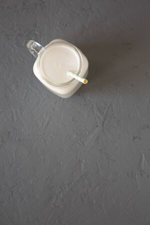 Coconut milk in a glass jar on a gray surface, top view. Flat lay, overhead, from above. Copy space.の写真素材