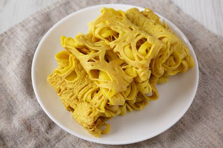 Homemade Net Crepe Roti Jala on a white plate on a white wooden background, low angle view....