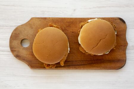 Homemade Burgers with fried chicken strips on a rustic wooden board on a white wooden background,...