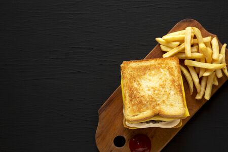 Fresh Grilled Cheese Burger with French Fries on a rustic wooden board on a black background, top...