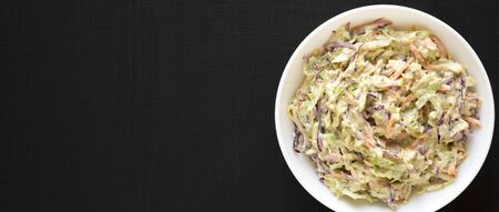 Homemade Creamy Broccoli Slaw in a white bowl on a black background, top view. Flat lay, from above, overhead. Copy space.の写真素材