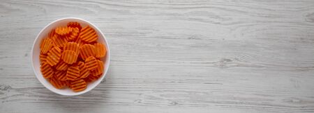 Fresh Raw Organic Carrot Chips in a white bowl over white wooden background, top view. From above, overhead, flat lay. Copy space.の写真素材