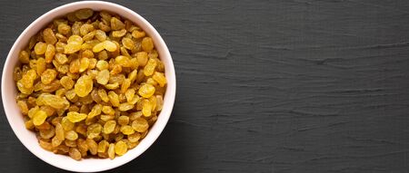 Golden Raisins in a Pink Bowl on a black background, top view. Flat lay, overhead, from above. Space for text.の写真素材