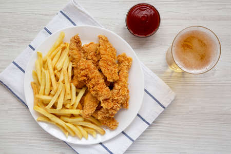 Homemade Crispy Chicken Tenders and French Fries with sauce and glass of cold beer, overhead view. Top view, from above, flat lay.の写真素材