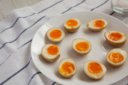 Homemade Unami Soy Sauce Eggs on a white plate, low angle view. Copy space.