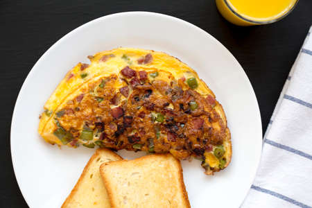 Homemade Denver Omelette on a white plate on a black background, top view. Flat lay, overhead, from...