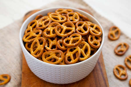 Crispy Pretzel Crackers in a Gray Bowl on a rustic wooden board, low angle view. Close-up.