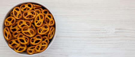 Crispy Pretzel Crackers in a Gray Bowl on a white wooden background, top view. Flat lay, overhead, from above. Space for text.の写真素材