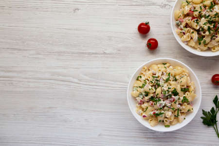 Homemade Macaroni Salad in white bowls on a white wooden background, top view. Flat lay, overhead,...