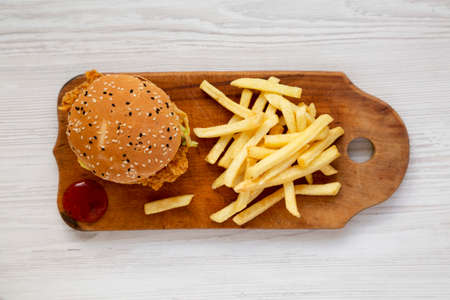 Homemade Chicken Strips Burger with French Fries and sour-sweet sauce on rustic board, top view. Flat lay, overhead, from above.の写真素材
