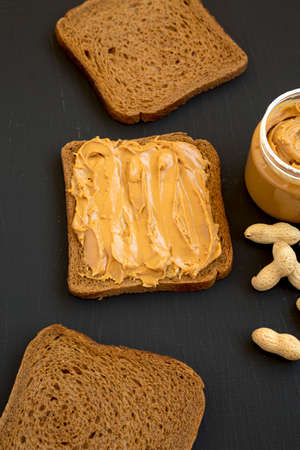 Piece of Bread with Peanut Butter on a black background, side view.