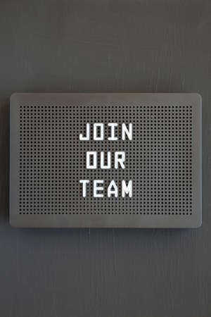 'Join our team' words on a black lightbox on a black surface, top view. Flat lay, overhead, from...