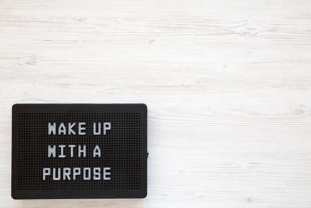 'Wake up with a purpose' words on a black lightbox on a white wooden background, top view. Copy space.の写真素材