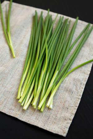 Raw Green Onions on a black surface, side view.の写真素材