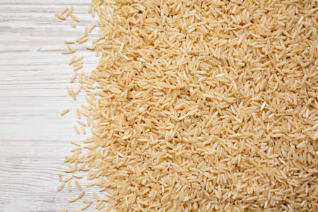 Dry Brown Rice on a white wooden background, top view. Overhead, from above, flat lay. Space for text.の写真素材