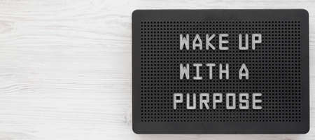 'Wake up with a purpose' words on a black lightbox on a white wooden background, top view. From above, overhead, flat lay. Copy space.の写真素材