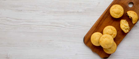 Homemade Cornbread Muffins on a rustic wooden board on a white wooden background, top view. Flat...