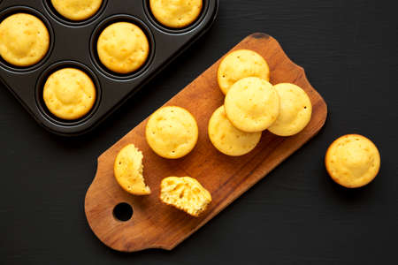 Homemade Cornbread Muffins on a rustic wooden board on a black surface, top view. Flat lay,...