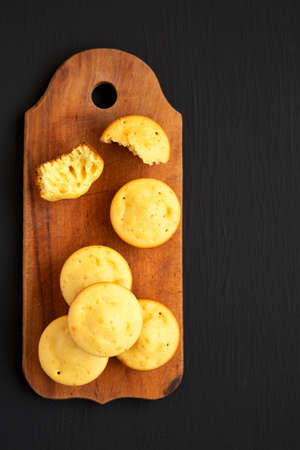 Homemade Cornbread Muffins on a rustic wooden board on a black surface, top view. Flat lay,...