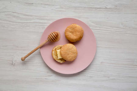 Homemade Flaky Buttermilk Biscuits on a pink plate on a white wooden table, top view. Flat lay,...