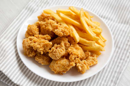 Homemade Fried Chicken Bites and French Fries on a plate, side view.の写真素材