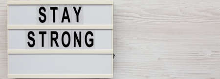 'Stay strong' on a lightbox on a white wooden surface, top view. Flat lay, overhead, from above....