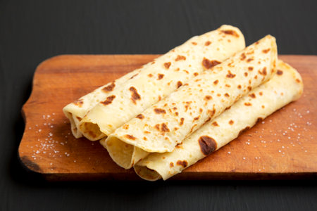 Homemade Norwegian Potato Flatbread (Lefse) with Butter and Sugar on a rustic wooden board on a...