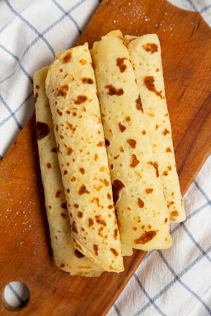 Homemade Norwegian Potato Flatbread (Lefse) with Butter and Sugar on a rustic wooden board on cloth,...