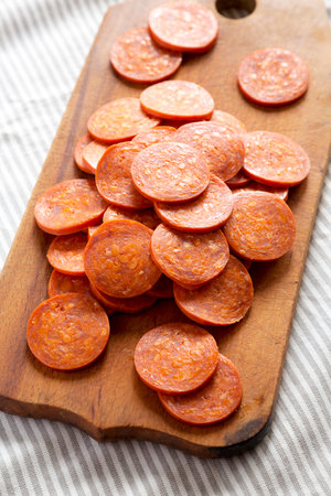 Italian Pepperoni Slices on a rustic wooden board on cloth, side view. Close-up.の写真素材