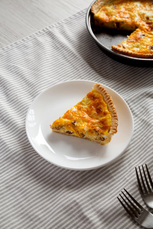 Homemade Bacon Quiche with Eggs and Cheddar Cheese on a white plate, high angle view.の写真素材